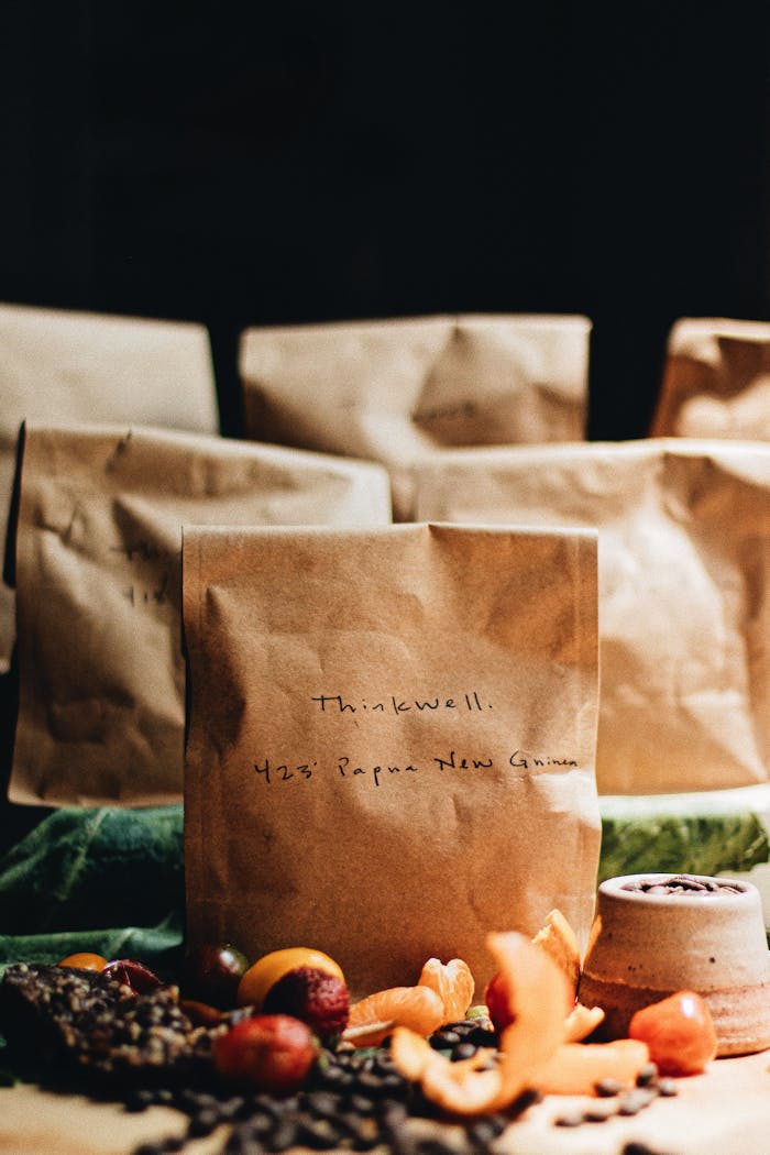 Artisan coffee in brown paper bags with fruits and beans. A rustic, warm setup perfect for branding.